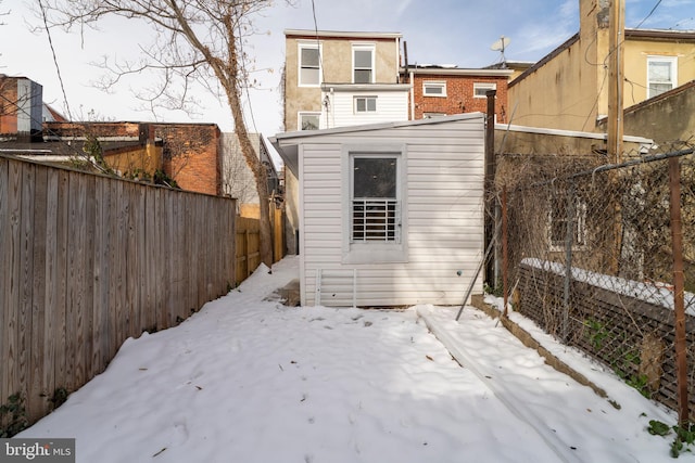 snow covered rear of property featuring a storage unit