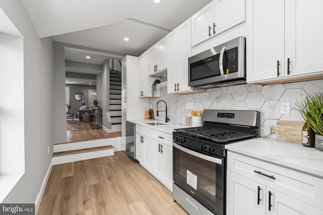 kitchen featuring sink, light stone counters, white cabinetry, and stainless steel appliances