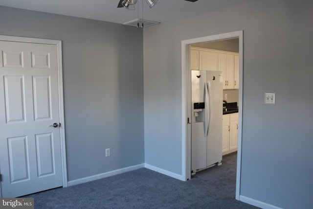 spare room featuring ceiling fan and dark colored carpet