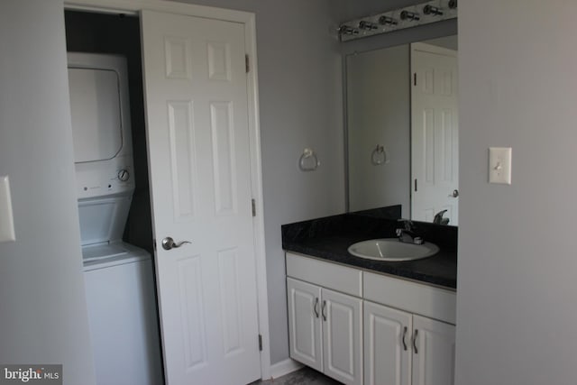 bathroom featuring stacked washing maching and dryer and vanity