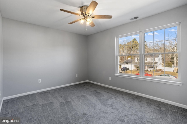 spare room with ceiling fan and dark colored carpet