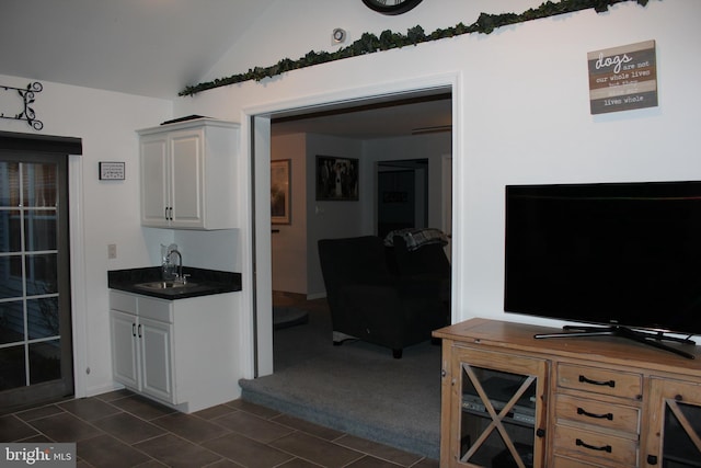 kitchen featuring white cabinetry, sink, dark carpet, and lofted ceiling