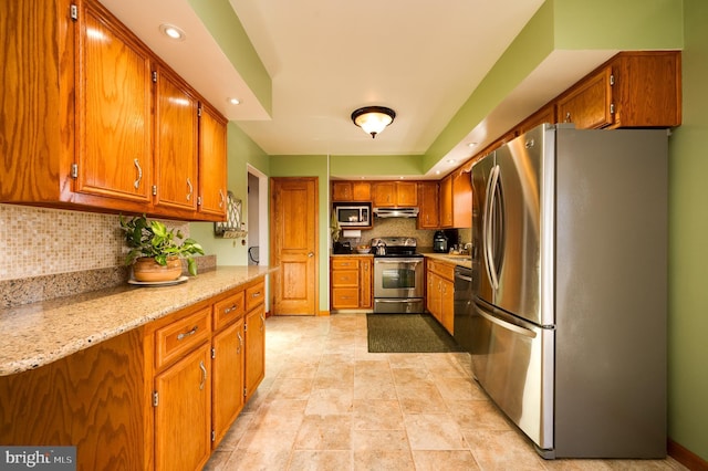 kitchen featuring light stone countertops, backsplash, and appliances with stainless steel finishes