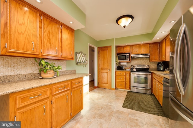 kitchen with light stone countertops, decorative backsplash, and stainless steel appliances