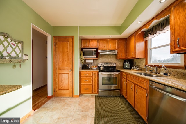 kitchen featuring light stone countertops, appliances with stainless steel finishes, tasteful backsplash, and sink