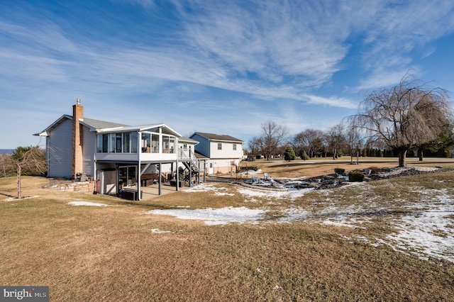 snow covered property featuring a yard, a patio, and a sunroom