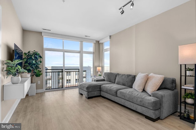 living room with expansive windows, track lighting, and light wood-type flooring