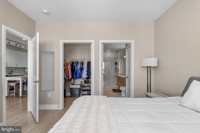 bedroom with ensuite bathroom, wood-type flooring, and a closet