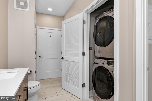 washroom with stacked washer and dryer and sink