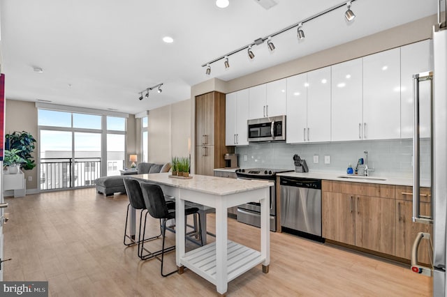 kitchen with white cabinets, appliances with stainless steel finishes, a kitchen bar, and sink