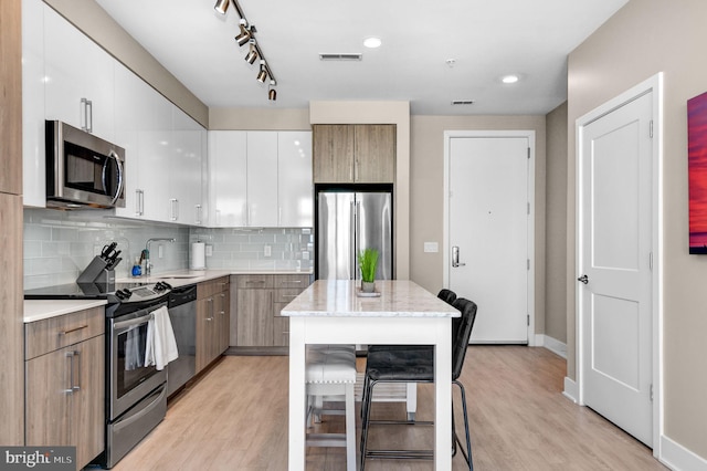 kitchen with white cabinets, a kitchen breakfast bar, a center island, and appliances with stainless steel finishes