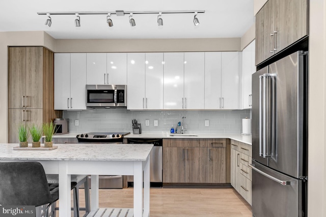 kitchen featuring decorative backsplash, appliances with stainless steel finishes, light stone countertops, sink, and white cabinetry