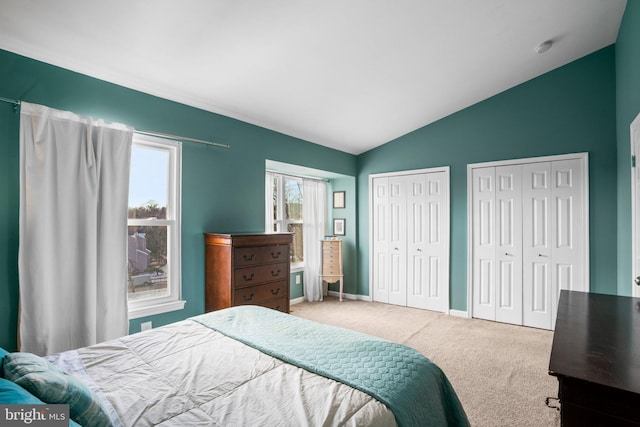 bedroom featuring two closets, carpet floors, and vaulted ceiling