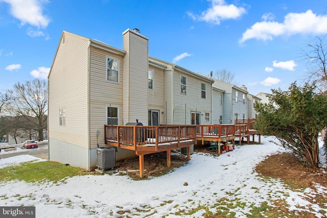 snow covered house featuring central air condition unit and a wooden deck