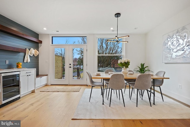 dining area featuring a chandelier, light hardwood / wood-style floors, beverage cooler, and french doors