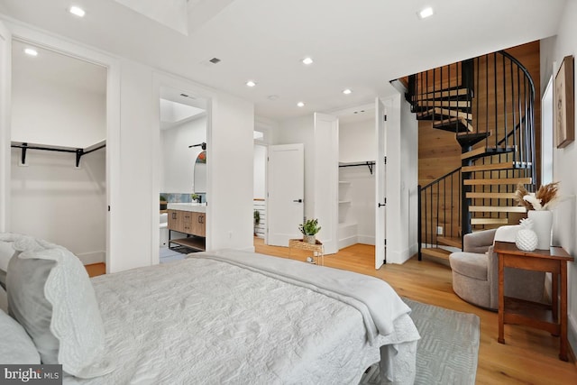 bedroom featuring a walk in closet, light wood-type flooring, and ensuite bathroom