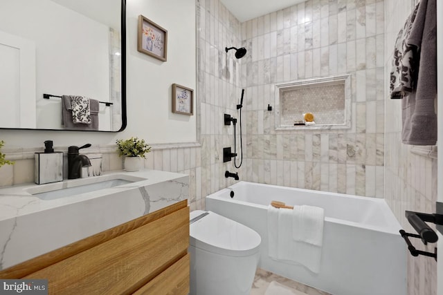 full bathroom with vanity, toilet, tiled shower / bath, and tile walls