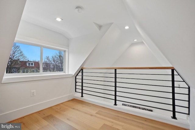 additional living space with hardwood / wood-style flooring and vaulted ceiling