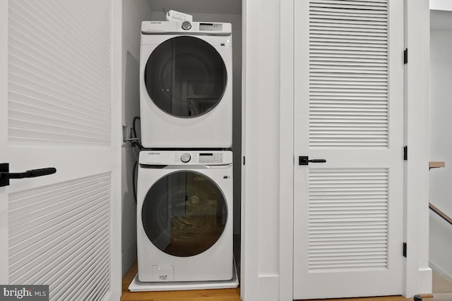 clothes washing area with stacked washing maching and dryer