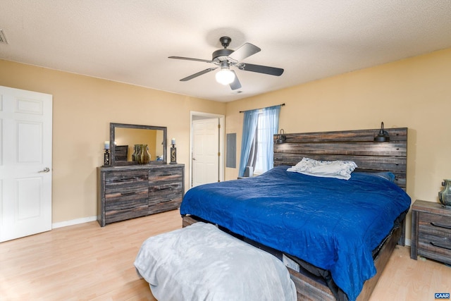 bedroom with ceiling fan, light hardwood / wood-style floors, and a textured ceiling