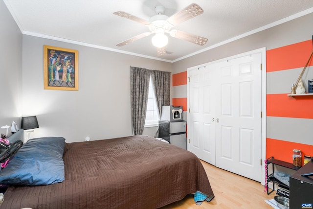 bedroom with a closet, ceiling fan, light hardwood / wood-style flooring, and crown molding