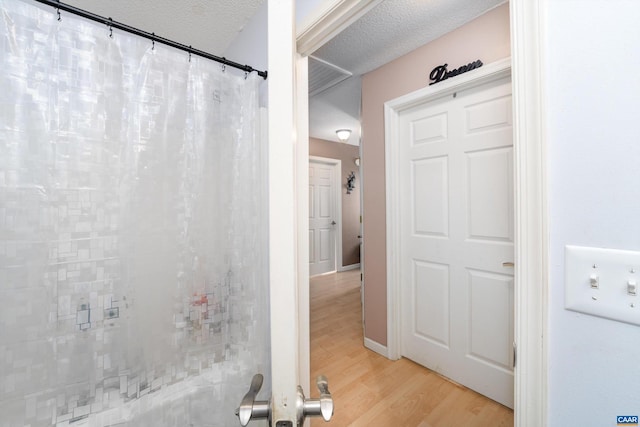 bathroom featuring hardwood / wood-style floors and a textured ceiling