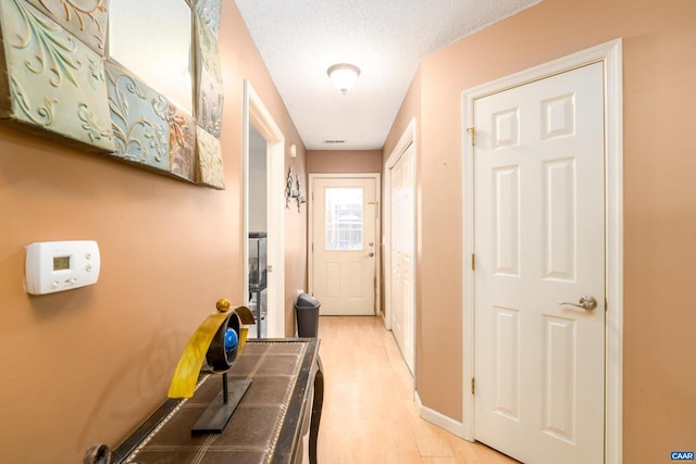 corridor featuring a textured ceiling and light hardwood / wood-style flooring