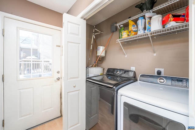 laundry area with independent washer and dryer and light hardwood / wood-style flooring