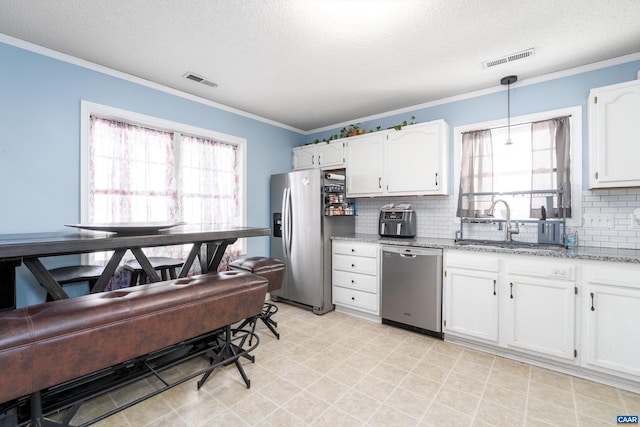 kitchen with white cabinets, decorative light fixtures, stainless steel appliances, and a textured ceiling