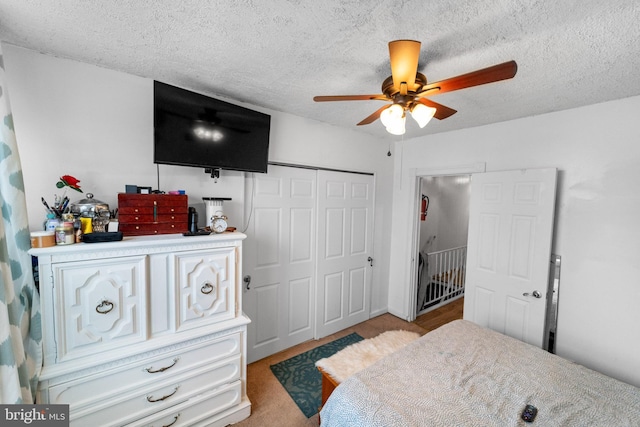 bedroom featuring ceiling fan, light colored carpet, a textured ceiling, and a closet