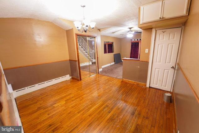 empty room with ceiling fan with notable chandelier, a baseboard radiator, and light hardwood / wood-style floors