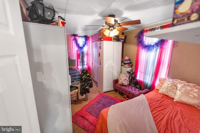 carpeted bedroom with a drop ceiling and ceiling fan