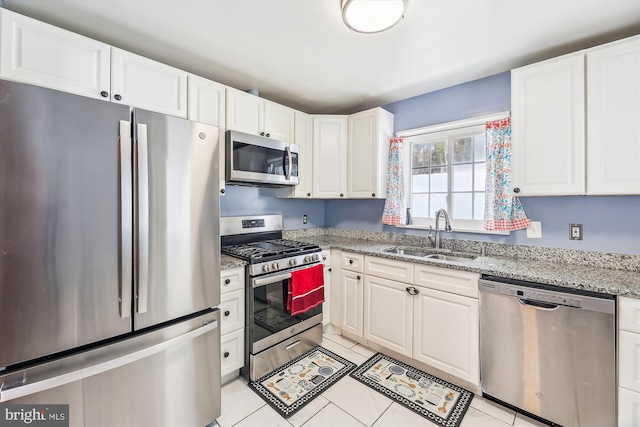 kitchen with appliances with stainless steel finishes, white cabinets, light tile patterned flooring, and sink