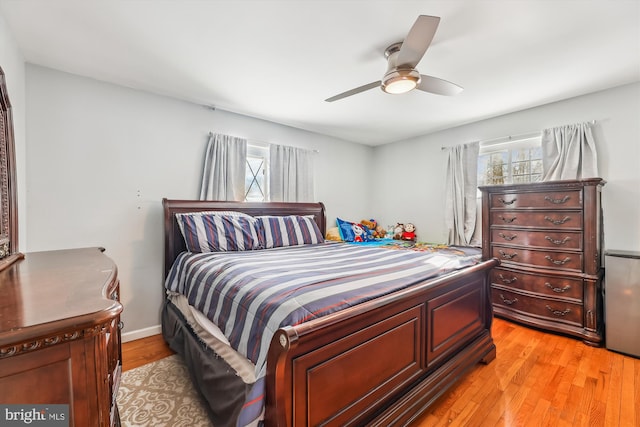 bedroom featuring ceiling fan, light hardwood / wood-style floors, and multiple windows