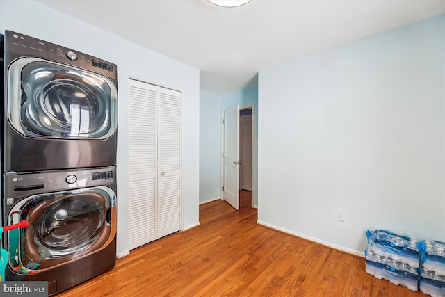 laundry room with hardwood / wood-style floors and stacked washer / drying machine