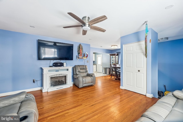 living room with ceiling fan, light wood-type flooring, and a high end fireplace