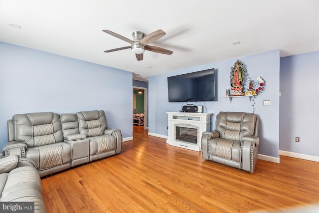 living room featuring a fireplace, ceiling fan, and light hardwood / wood-style floors