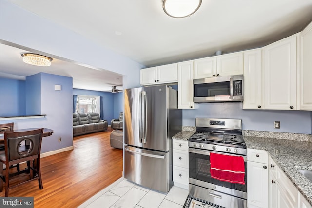 kitchen featuring appliances with stainless steel finishes, white cabinetry, and dark stone counters