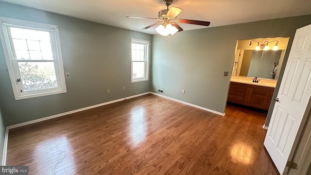 unfurnished bedroom with ensuite bath, ceiling fan, sink, and dark wood-type flooring