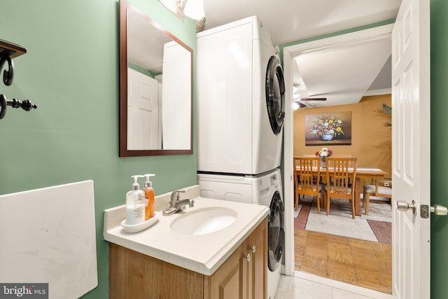 bathroom featuring ornamental molding, vanity, ceiling fan, stacked washer / dryer, and tile patterned flooring