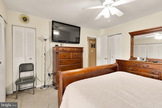 bedroom featuring light carpet, two closets, and ceiling fan