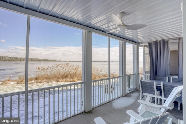 sunroom with ceiling fan and a water view