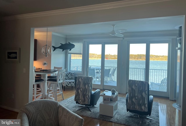 living room with ceiling fan with notable chandelier, ornamental molding, a water view, and plenty of natural light