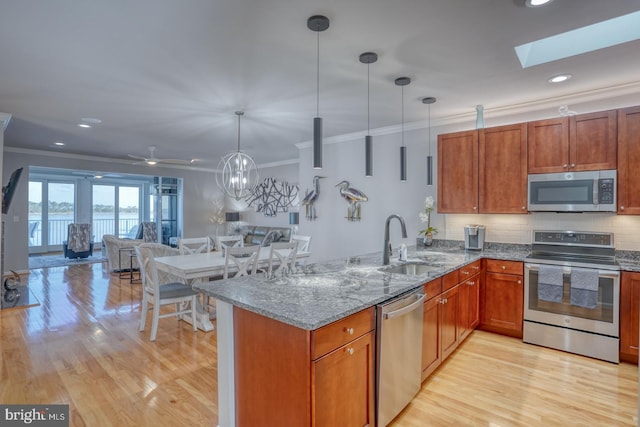 kitchen with sink, stainless steel appliances, kitchen peninsula, and decorative light fixtures