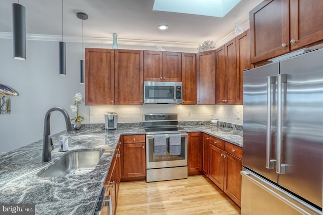 kitchen featuring sink, dark stone counters, hanging light fixtures, and appliances with stainless steel finishes