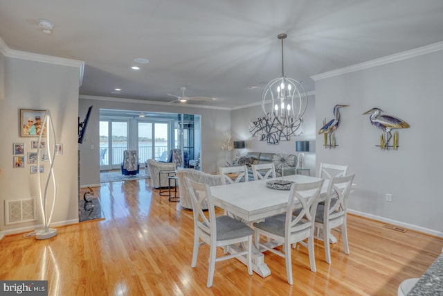 dining area with light wood-type flooring, ceiling fan with notable chandelier, and crown molding