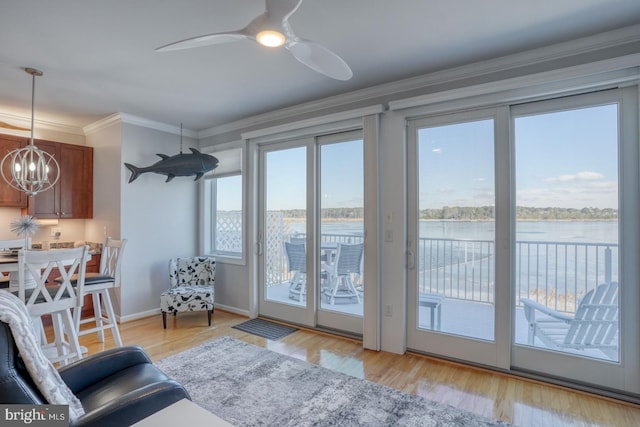 doorway with light wood-type flooring, ceiling fan with notable chandelier, a water view, and crown molding