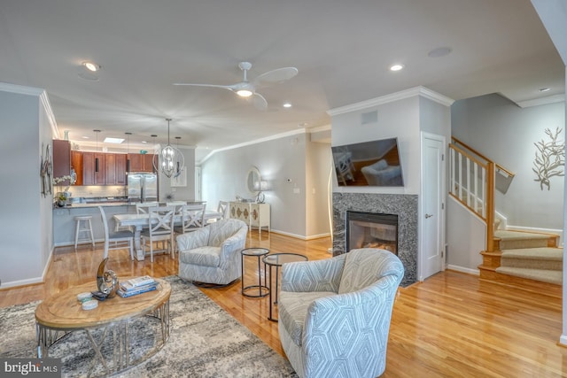 living room featuring light wood-type flooring, ceiling fan, and ornamental molding