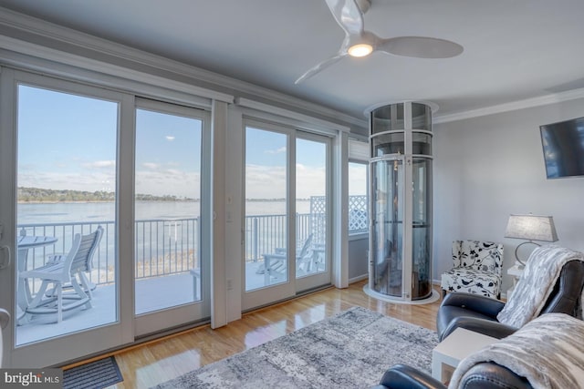 living room with light wood-type flooring, a water view, a healthy amount of sunlight, and ornamental molding