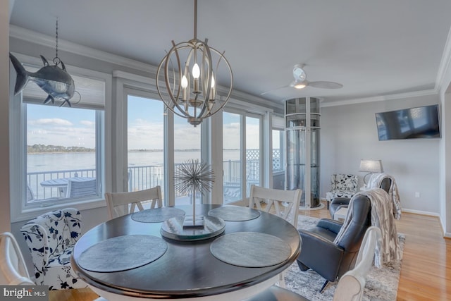 dining room with a water view, light hardwood / wood-style flooring, a wealth of natural light, and ornamental molding